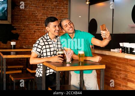 Junge Homosexuell paar Selfie beim Bier trinken an der Bar Stockfoto