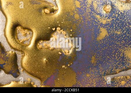 Stapel von Gold Pailletten auf blauen flüssigen Tinte Hintergrund. Abstraktes Muster. Stockfoto