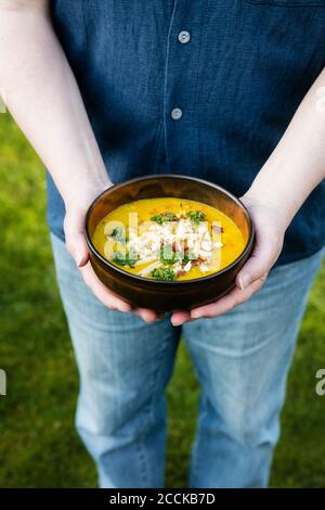 Mans Hände halten Schüssel mit Dal von Linsen, Kartoffeln und Gemüse Stockfoto