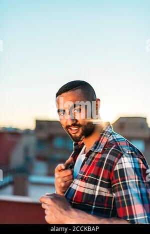 Lächelnder Mann gestikuliert, während er auf dem Dach in der Stadt steht Stockfoto