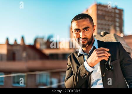 Lächelnder Geschäftsmann, der auf dem Dach eine Sonnenbrille hinstellt Stockfoto
