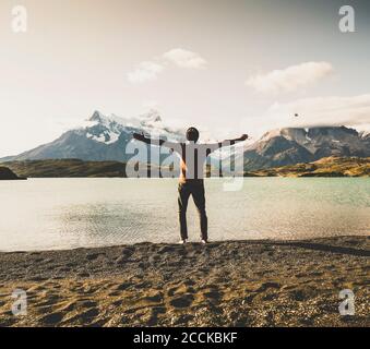 Mann, der mit ausgestreckten Armen am Pehoe-See im Torres Del Paine National Park Patagonia, Südamerika, steht Stockfoto