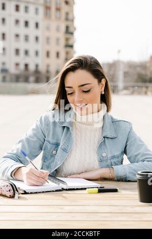 Junge Frau, die am Tisch auf dem Universitätscampus studiert Stockfoto
