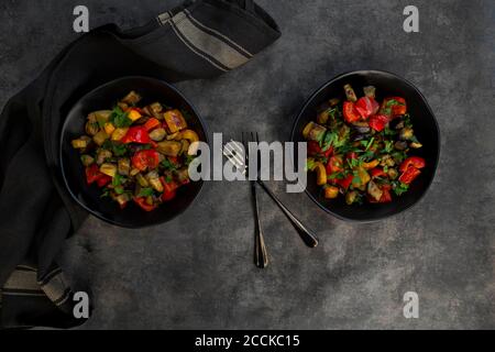 Zwei Schüsseln gebratener veganer Salat mit Auberginen, Paprika und Petersilie Stockfoto