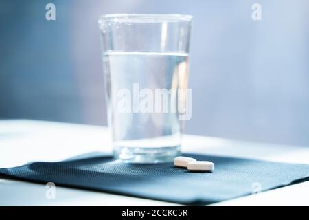 Tabletten und Wasserglas auf Serviette Stockfoto