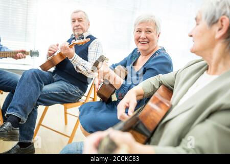 Senioren in Altersheim Besuch Gitarre Klasse, Musik zu machen Stockfoto