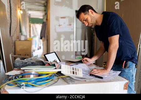 Mann, der an Bauplan und Farbmuster arbeitet Stockfoto