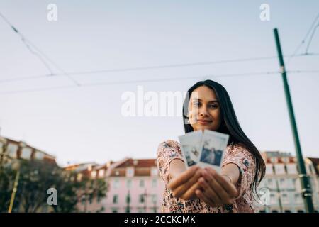 Junge Frau zeigt Fotos von ihr in der Stadt Stockfoto