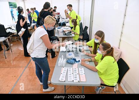 22. August 2020, Sachsen, Leipzig: Eine Testperson (vorne links) steht vor dem Beginn eines Großexperiments der Universitätsmedizin Halle/Saale am Check-in. Rund 1400 Besucher nehmen an dem Experiment 'Restart-19' Teil, bei dem der Popsänger Tim Bendzko bei einem Konzert auftritt. Die Wissenschaftler wollen mit Sensoren und anderen Hilfsmitteln Gehwege überwachen und fluoreszierendes Desinfektionsmittel soll sichtbar machen, welche Oberflächen oft berührt werden. Die Forscher hoffen auch, den Flug von Aerosolen zu verfolgen - die kleinsten Gemische von Partikeln, die das Virus tragen könnten. Stockfoto