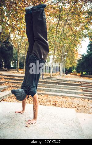 Junger Mann beim Handstand im öffentlichen Park während der Herbstsaison Stockfoto