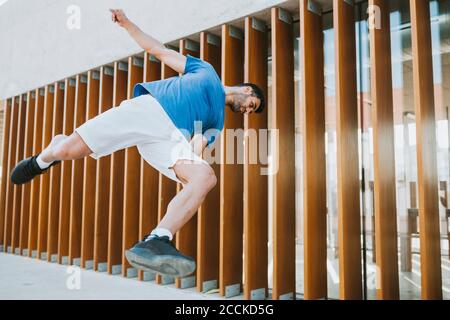 Junger Mann Durchführung Stunt gegen gebaute Struktur in der Stadt Stockfoto