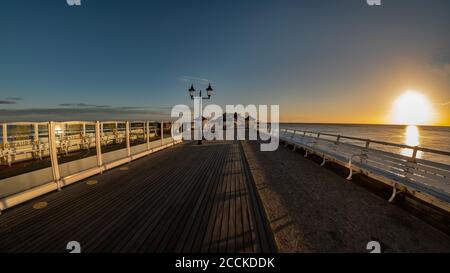 Fischaugen Blick entlang der hölzernen Promenade des viktorianischen Pier in der Küstenstadt Cromer an der North Norfolk Küste bei Sonnenaufgang. Absichtliche Verzerrung Stockfoto