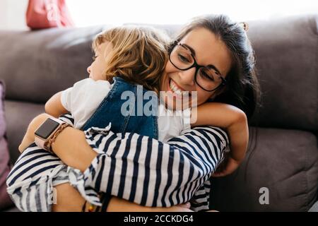 Nahaufnahme einer glücklichen Mutter, die ihre Tochter umarmt, während sie auf dem Sofa sitzt Zu Hause