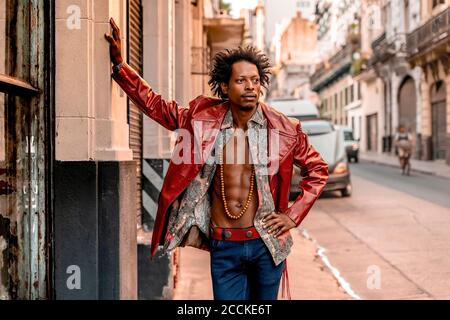 Nachdenklicher Retro-Mann in Lederjacke, während er auf dem Bürgersteig steht An sonnigen Tagen Stockfoto