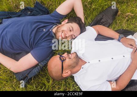 Lächelnd Gay paar Blick auf einander beim Liegen auf Grasland im Park Stockfoto