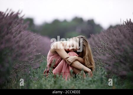 Frau, die im Lavendelfeld sitzt Stockfoto