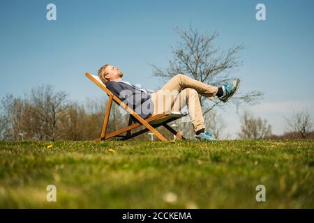 Blick auf die Oberfläche des Geschäftsmannes, der sich auf einem Stuhl im Park entspannen kann An sonnigen Tagen Stockfoto