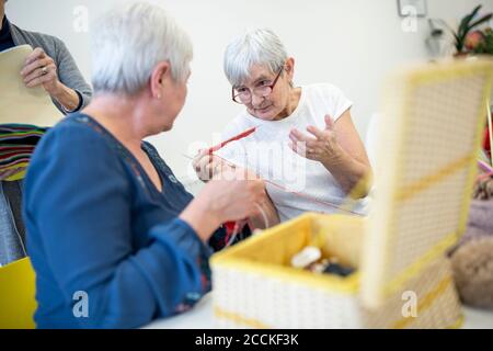 Zwei ältere Frauen im Altersheim sprechen beim Stricken Handarbeitsgruppe Stockfoto