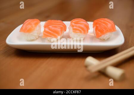 Essstäbchen und Sushi mit Lachs auf der Bambusmatte Stockfoto