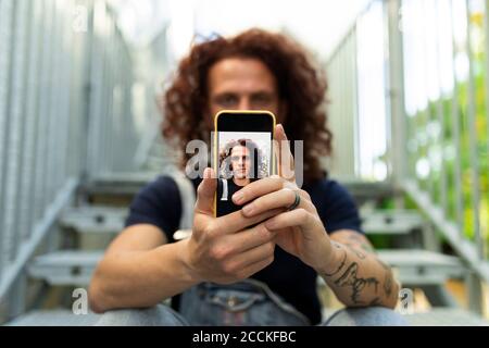 Mann nimmt Selfie, während er auf der Treppe sitzt Stockfoto