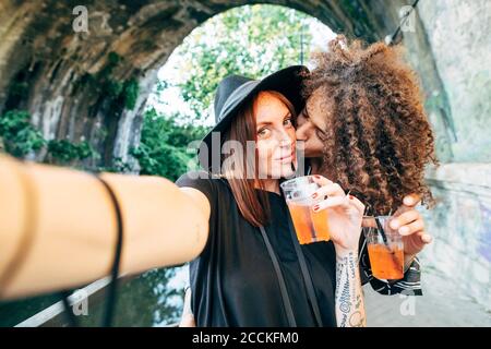 Romantischer Mann, der sich im Park auf die Wange der Freundin küsst Stockfoto