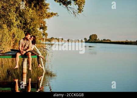 Das Paar spiegelte sich im Wasser auf dem Steg an einem See wider Stockfoto