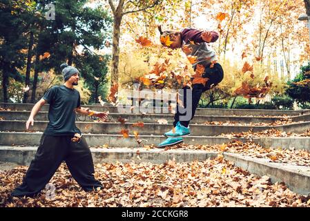 Junger Mann, der im Herbst einen Freund im Park hüpft Stockfoto