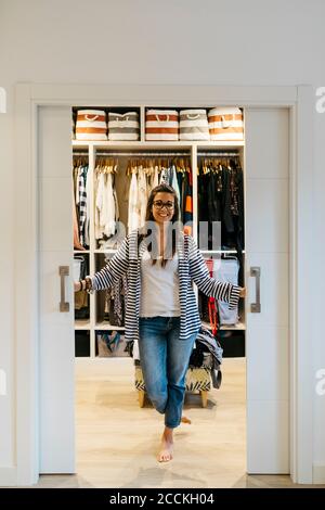 Lächelnde junge Frau, die zu Hause Türen in der Garderobe öffnet Stockfoto