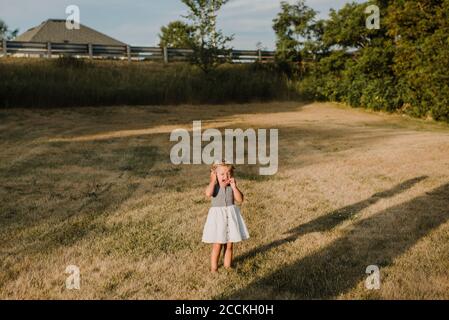 Weinendes kleines Mädchen, das allein auf einer Wiese steht Stockfoto