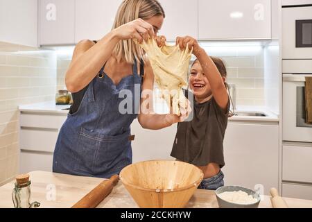 Mutter mit fröhlichen Tochter kneten Pizzateig in der Küche bei Zu Hause Stockfoto