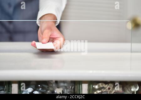 Nahaufnahme einer männlichen Hand, die eine Kreditkarte durch eine Sicherheitspartition auf einem unscharf Hintergrund hält. Arbeits- und Sicherheitskonzept. Stockfoto