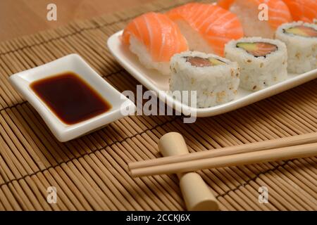 Essstäbchen, Sojasauce und Sushi auf der Bambusmatte Stockfoto