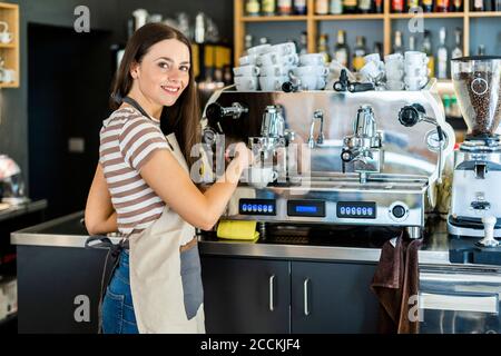 Glückliche Barista, die im Café eine Kaffeemaschine benutzt Stockfoto