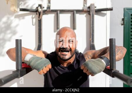 Nahaufnahme eines kahlen reifen Mannes mit Mundschutz, der gegen die Wand trainiert Im Hof Stockfoto