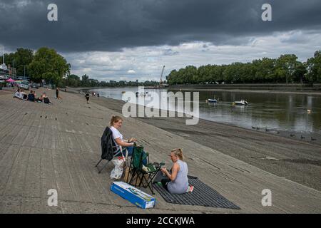 PUTNEY LONDON, Großbritannien - 23. August 2020 Menschen, die ein Picknick am Putney Flussufer an der Themse machen, während sich an einem gemischten Tag Gewitterwolken mit Sonneneinbruch bewegen. Die Prognose ist für wechselhaftes Wetter nächste Woche mit Sturmwind und einem Rückgang der Temperaturen. Kredit: amer ghazzal/Alamy Live Nachrichten Stockfoto