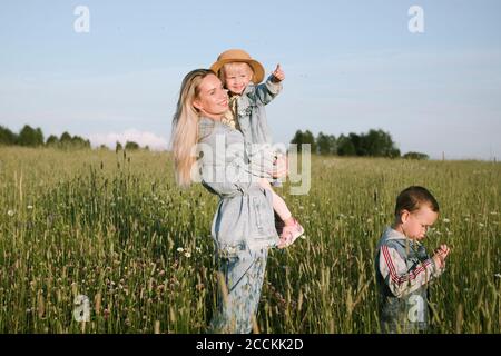 Lächelnde Mutter mit zwei Kindern, die auf dem Feld gehen Stockfoto