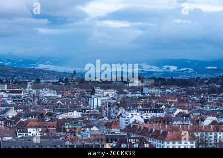 Schweiz, Zürich, Sturmwolken über der Stadt mit schneebedeckten Bergen im Hintergrund, Luftaufnahme Stockfoto