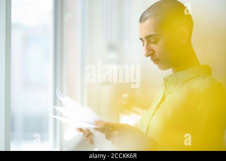 Geschäftsfrau beim Lesen von Zeitungen am Fenster im Loft-Büro Stockfoto