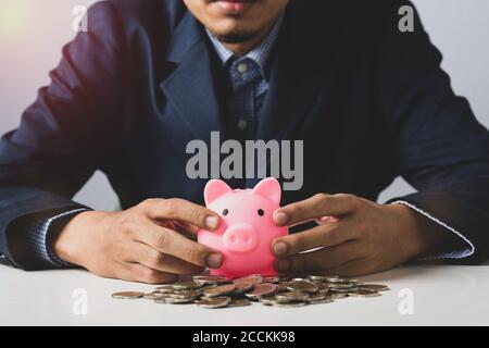 Hand of Business Mann mit Münze in Sparschwein mit Geldstapel wachsendes Wachstum Geld sparen, Konzept Invesment für finanzielle Freiheit Geschäft setzen. Stockfoto