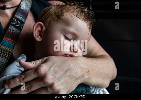 Mutter umarmt schlafenden Baby Sohn Stockfoto