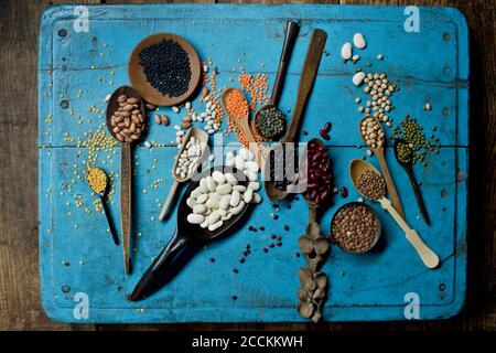 Verschiedene Bohnen und Linsen auf blauer rustikaler Holzoberfläche Stockfoto