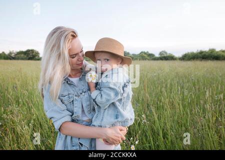 Mutter hält ihre Tochter auf dem Feld Stockfoto