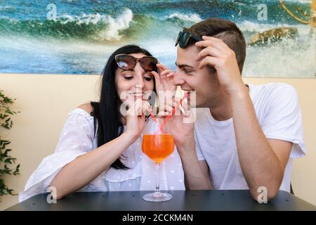 Glückliches junges Paar, das einen Aperitif teilt Stockfoto