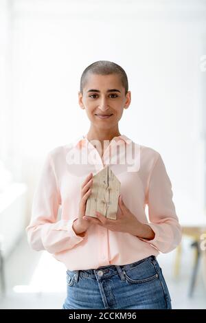 Porträt einer selbstbewussten Frau mit Hausmodell Stockfoto