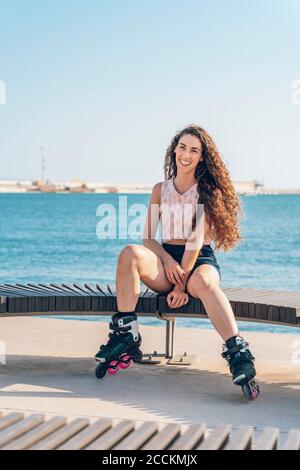 Junge Frau mit Inline-Skates auf der Bank sitzen Stockfoto