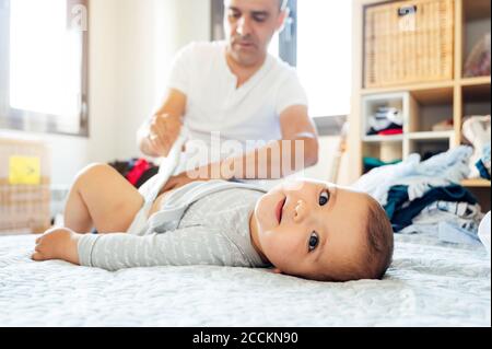 Vater mit Baby Junge auf dem Bett liegend, Windeln ändern Stockfoto