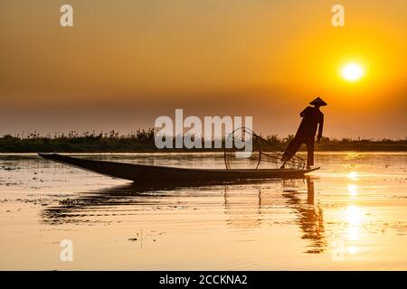 Myanmar, Shan Staat, Silhouette der traditionellen Intha Fischer auf Inle See bei Sonnenuntergang Stockfoto