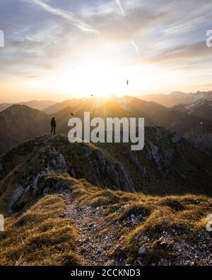 Wandererin, die während des Sonnenuntergangs am Aussichtspunkt steht, Saeuling, Bayern, Deutschland Stockfoto