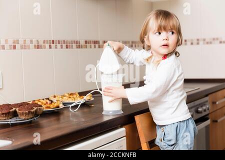 Mädchen Schlagsahne in der Küche Stockfoto