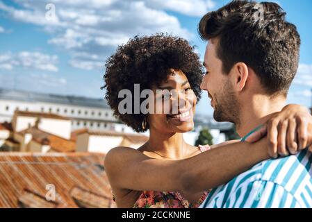 Romantisches Paar mit mittleren Erwachsenen, das sich an sonnigen Tagen gegen den Himmel umarmt Stockfoto